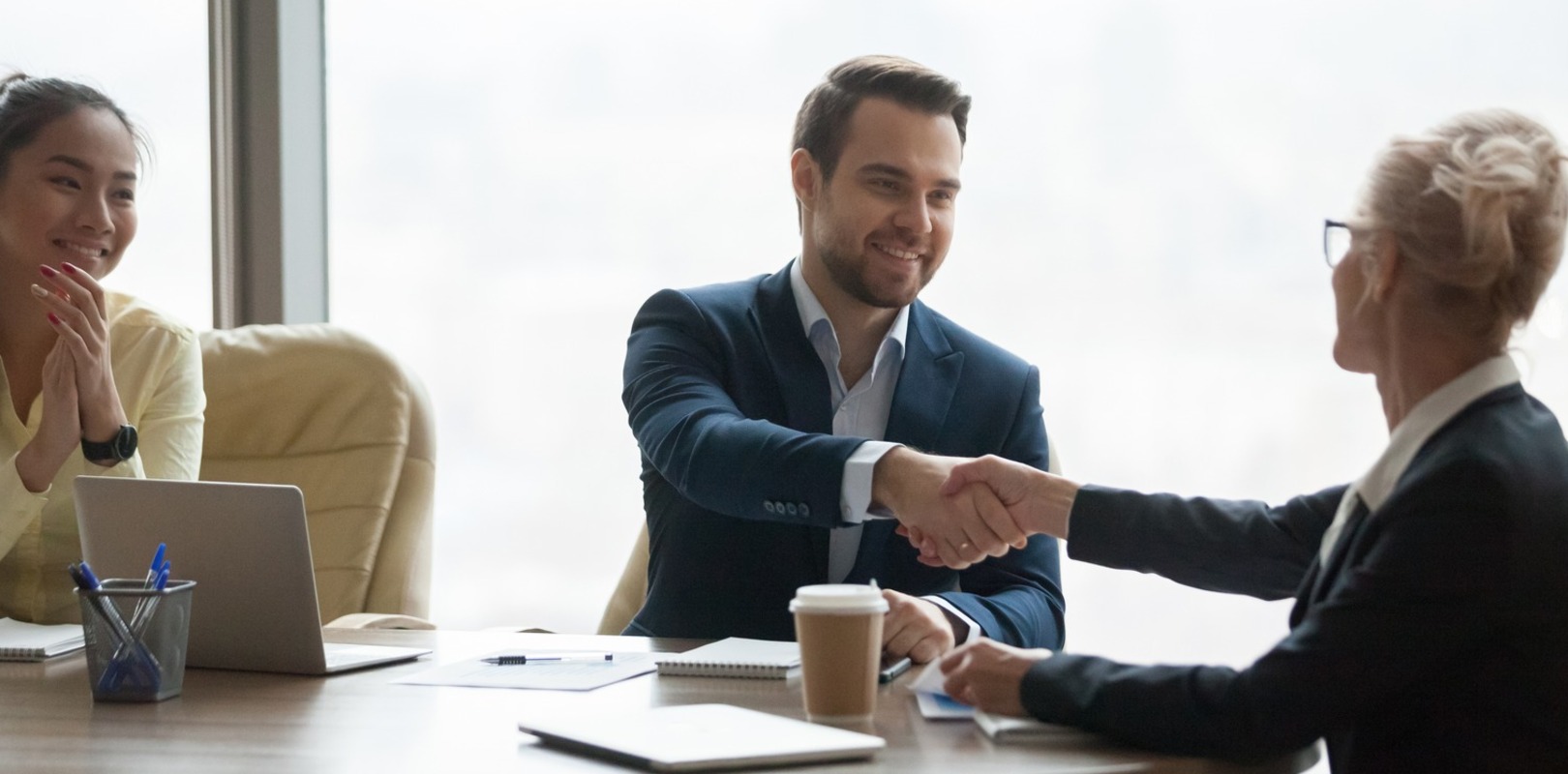 recruitment team shaking hands with client in a meeting